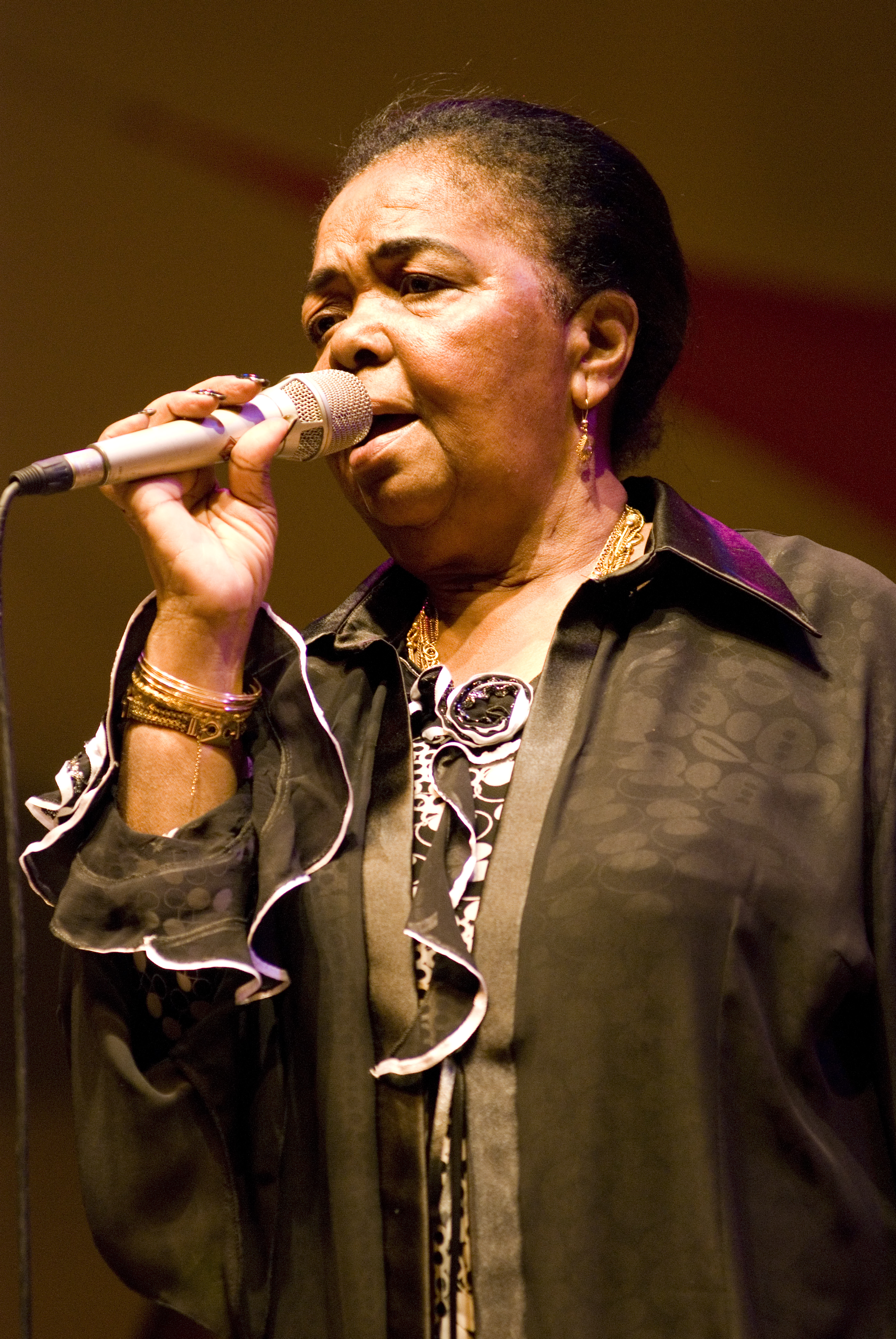 Cesária Évora chantant sur scène, photographiée par Silvio Tanaka en 2008.